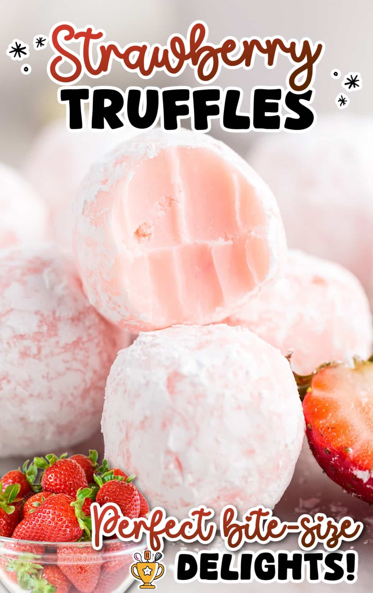 Pile of bite-sized strawberry truffles rolled in powdered sugar, with a halved truffle front and center revealing a soft, creamy strawberry filling.