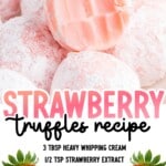 Strawberry truffles piled together with one truffle cut open to show the smooth strawberry-flavored white chocolate interior, dusted heavily with powdered sugar.
