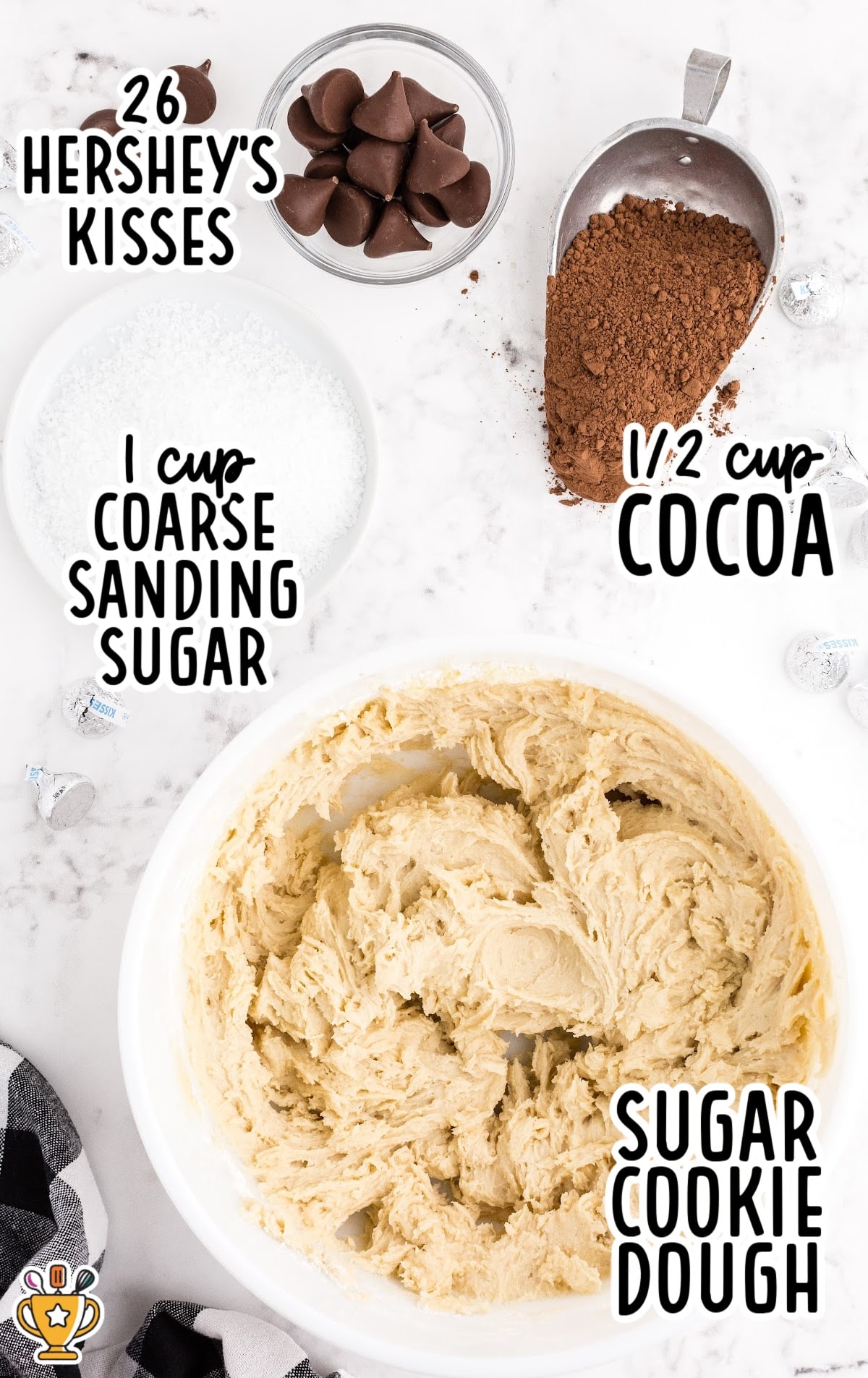 Labeled ingredients for chocolate kiss cookies including sugar cookie dough in a bowl, unsweetened cocoa powder, coarse sanding sugar, and 26 Hershey’s Kisses.