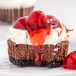 Finished black forest mini cheesecake with whipped topping, cherry pie filling, and chocolate shavings, presented as a recipe card image highlighting the layered chocolate cheesecake and crust.
