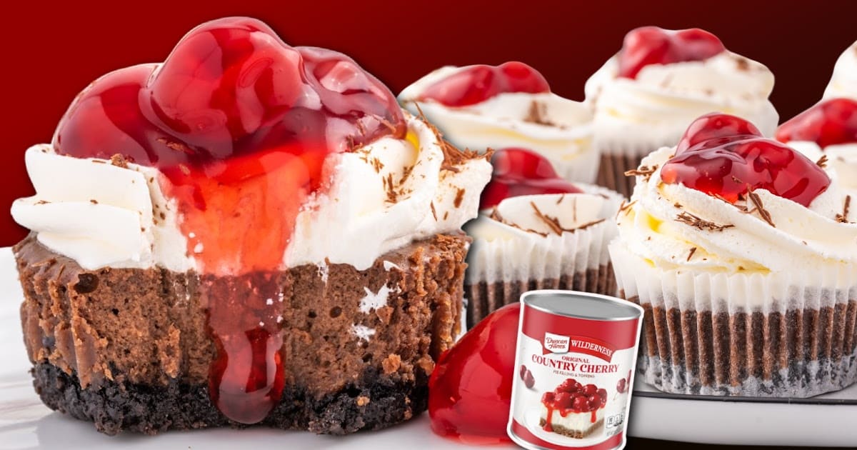 Group of finished black forest mini cheesecakes arranged on a tray, each topped with whipped cream and cherry pie filling, with a can of cherry pie filling visible beside them.