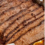 Close-up of sliced beef brisket resting in a foil pan filled with rich cooking juices. The brisket appears moist and tender with visible seasoning. Text on the image reads &ldquo;Slow Cooking Brisket in Oven!&rdquo; and &ldquo;Fall-apart Tender!&rdquo;