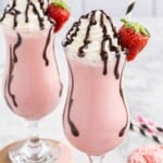 Two strawberry mudslide cocktails topped with whipped cream, chocolate drizzle, and fresh strawberry garnishes.