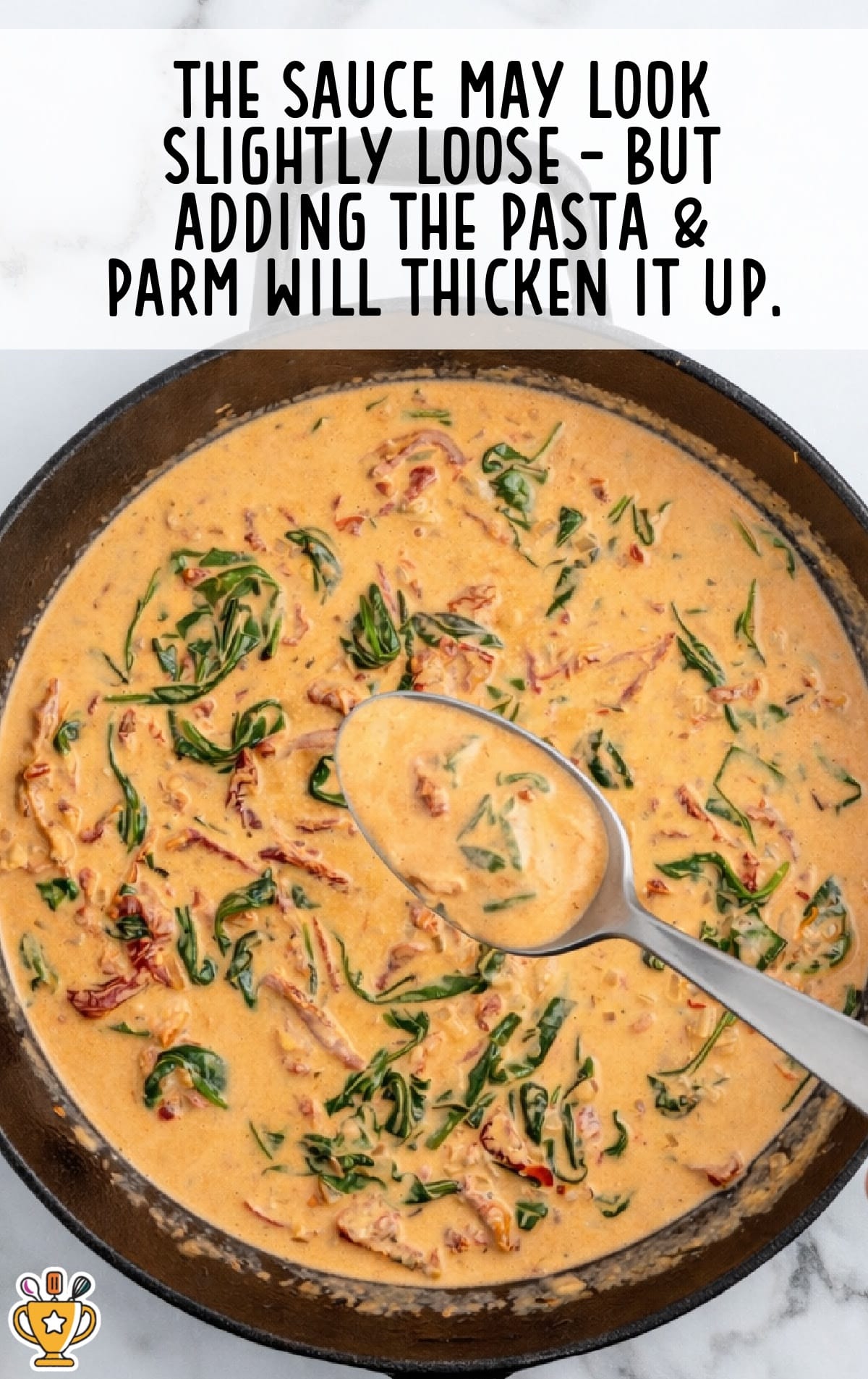 Creamy Tuscan chicken pasta sauce in a skillet before adding pasta, showing a slightly loose consistency with sun-dried tomatoes and spinach as the sauce thickens with parmesan and pasta.