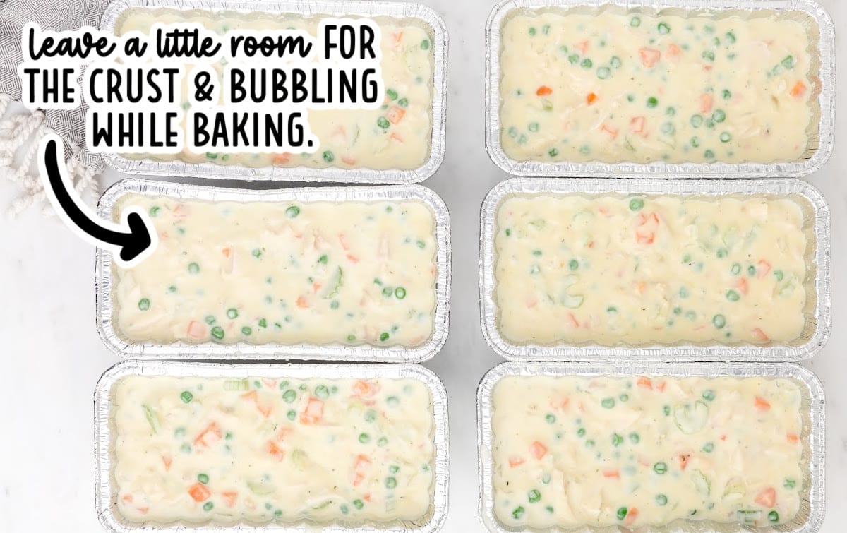 Six foil loaf pans filled with chicken pot pie filling arranged on a white surface, with on-image text noting to leave room for the crust and bubbling during baking.