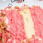 Vertical Strawberry Crunch Cake pin featuring a close-up slice with pink strawberry cake layers, creamy vanilla cheesecake center, cookie crumb coating, fork bite in the foreground, and text overlay reading &ldquo;Strawberry Shortcake Cheesecake&rdquo; and &ldquo;Bakery-Style Made Simple.&rdquo;