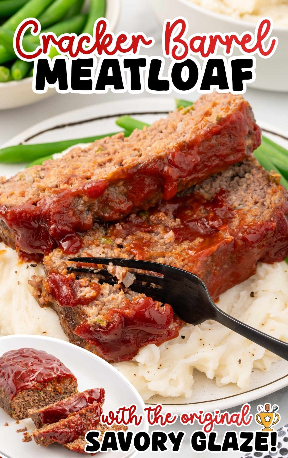 Overhead angled view of a glazed Cracker Barrel meatloaf on a white oval platter with two slices cut and fanned slightly forward. The ketchup glaze appears smooth and glossy across the top. A small dish of extra ketchup and a bowl of realizing green beans sit nearby on a light countertop.