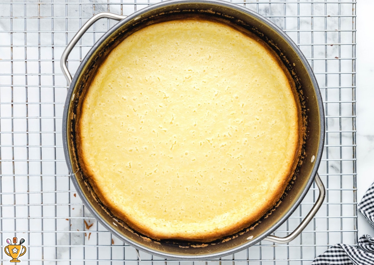 A baked cheesecake cooling in a baking pan