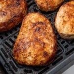 Crispy, seasoned boneless pork chops cooking inside an air fryer basket, showing browned exterior and juicy texture.