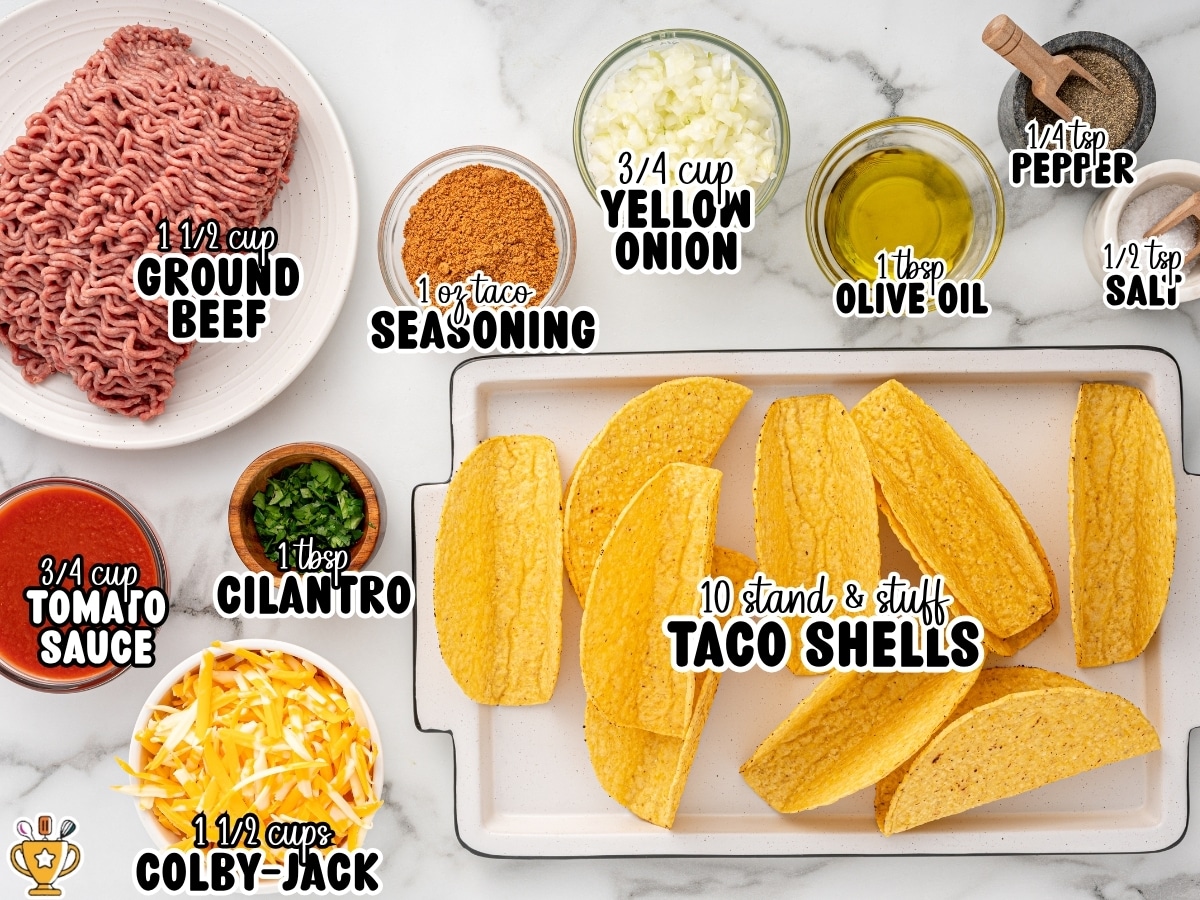 Overhead ingredients photo for baked tacos with labeled measurements: “¾ cup TOMATO SAUCE,” “1 ½ cup GROUND BEEF,” “1 ½ cups COLBY-JACK,” “1 tbsp CILANTRO,” “1 oz taco SEASONING,” “¾ cup YELLOW ONION,” “1 tbsp OLIVE OIL,” “¼ tsp PEPPER,” “½ tsp SALT,” and “10 stand & stuff TACO SHELLS,” arranged around a baking dish of taco shells.