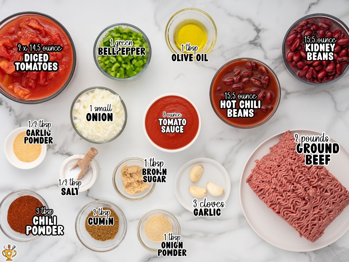 Ingredients for crockpot chili including ground beef, diced tomatoes, kidney beans, chili beans, tomato sauce, green bell pepper, onion, garlic, olive oil, chili powder, cumin, onion powder, garlic powder, salt, and brown sugar arranged in bowls on a marble surface.