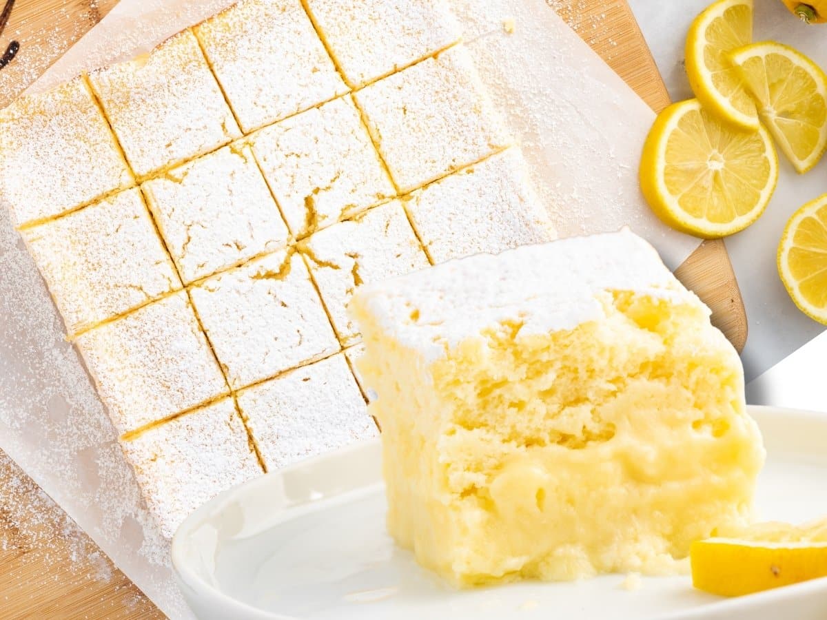Overhead view of lemon custard cake cut into squares and dusted with powdered sugar on parchment paper, with fresh lemon slices and a plated slice showing the soft cake layer and creamy custard center.