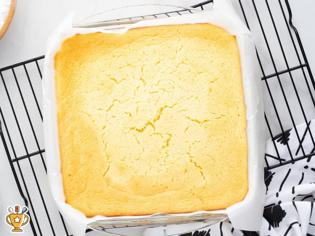lemon custard cake fully baked in 8x8 pan with golden edges and set center on cooling rack