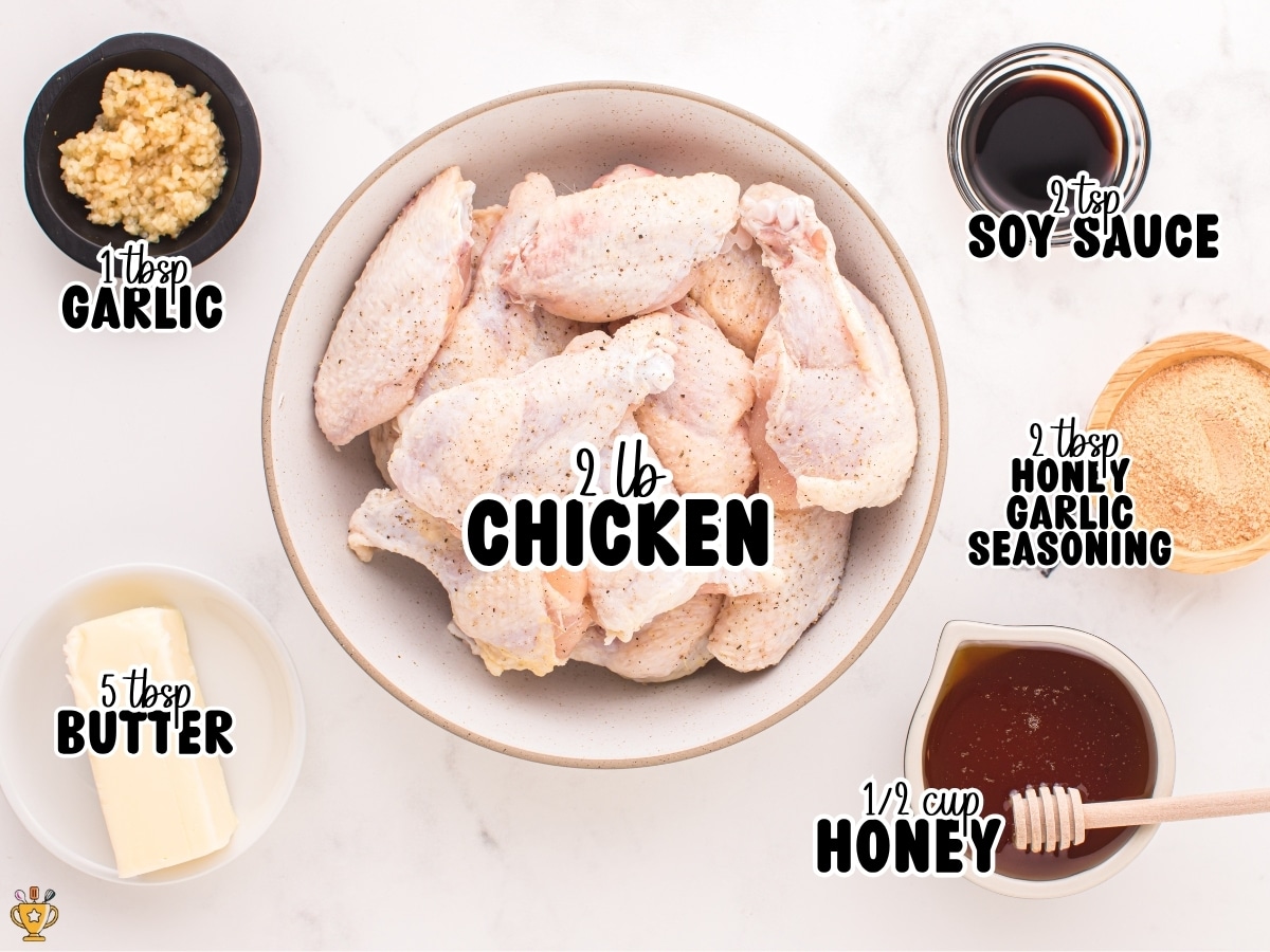 Overhead view of ingredients for air fryer honey garlic chicken labeled on a light background, including chicken, garlic, butter, soy sauce, honey garlic seasoning, and honey