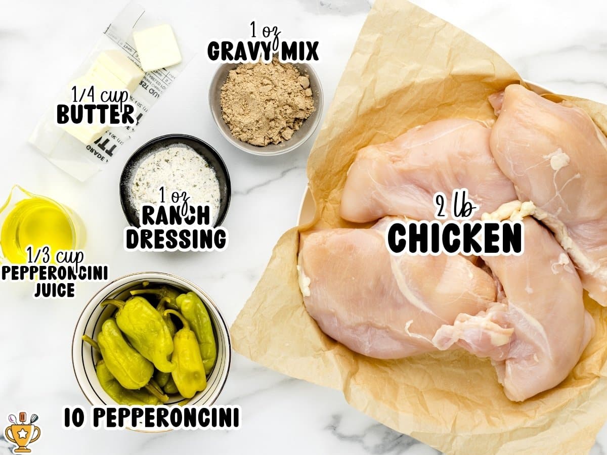 Ingredients for Mississippi chicken including 2 pounds raw boneless skinless chicken breasts, 1 ounce ranch dressing mix, 1 ounce gravy mix, ⅓ cup pepperoncini juice, ¼ cup butter, and whole pepperoncini peppers displayed on a marble surface.
