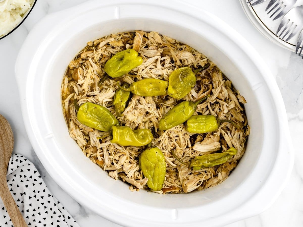 Slow cooker Mississippi chicken with shredded chicken in a buttery, tangy sauce, topped with whole pepperoncini peppers and served directly in the crockpot.