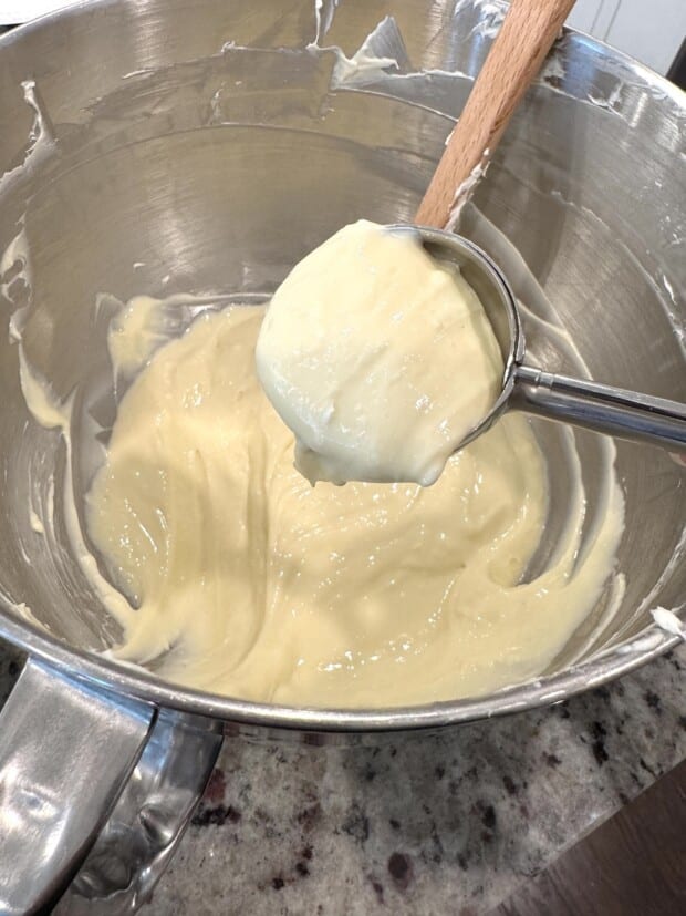 Smooth cheesecake batter in mixing bowl scooped with a cookie scoop