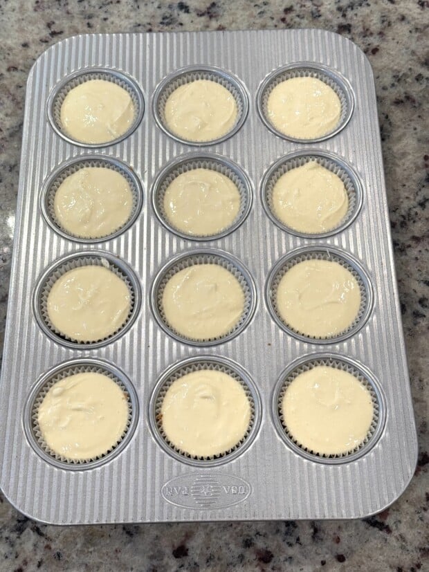Cheesecake batter evenly portioned into muffin liners over baked crusts