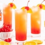 Recipe card image for a Sex on the Beach drink with layered orange and cranberry colors, orange slices, cherries, vodka, juice, and cocktail garnishes.