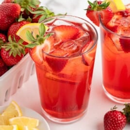 Feature image of Southern Strawberry Sweet Tea in tall glasses with ice, sliced strawberries, lemon wedges, and fresh strawberries on the side.