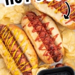 Pinterest graphic for air fryer hot dogs showing toasted hot dogs in buns topped with ketchup and mustard, potato chips, a small air fryer basket with hot dogs, and on-image text that reads &ldquo;AIR FRYER HOT DOGS&rdquo; and &ldquo;PERFECT FOR BUSY NIGHTS!&rdquo;