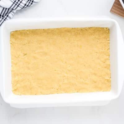 Pressed lemon pie bar crust in a white 9x13 baking dish