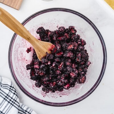 Fresh blackberry filling with sugar and lemon juice in a glass mixing bowl