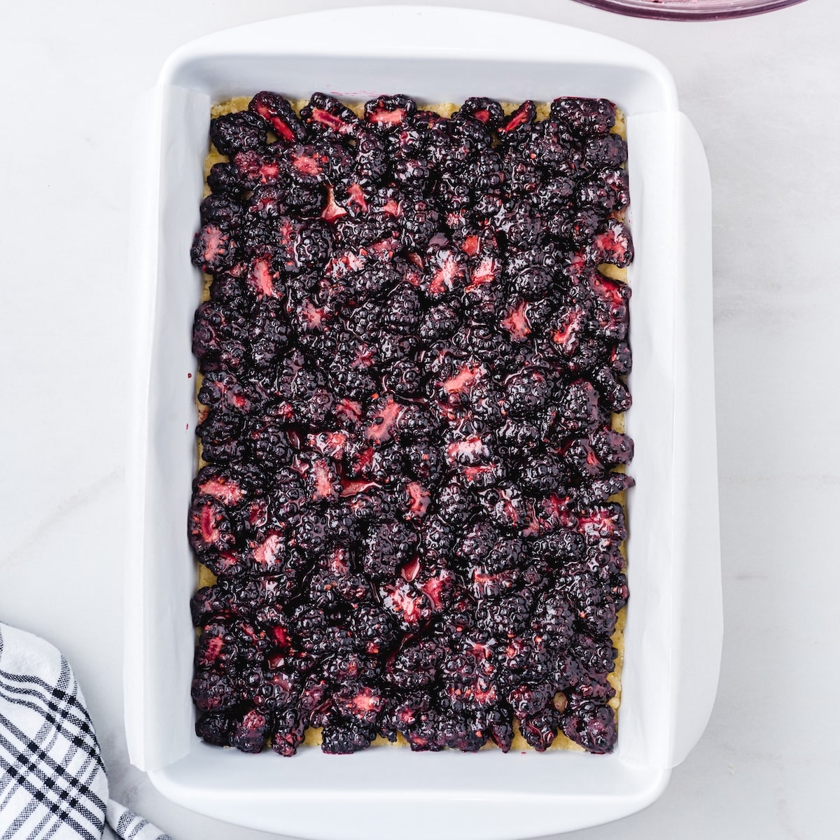 Blackberry filling spread over the crust in a white 9x13 baking dish