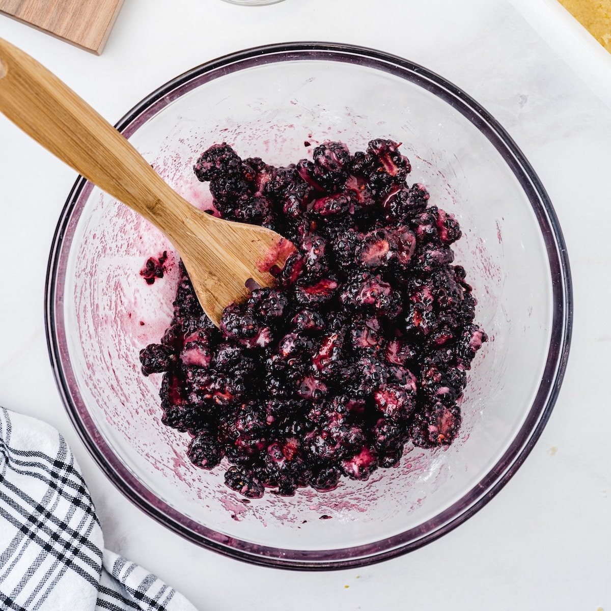 Fresh blackberry filling with sugar and lemon juice in a glass mixing bowl