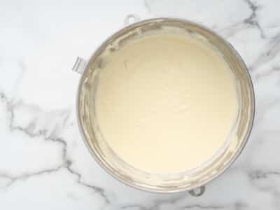 Smooth lemon cheesecake batter in a stand mixer bowl, ready for the blueberries to be folded in.