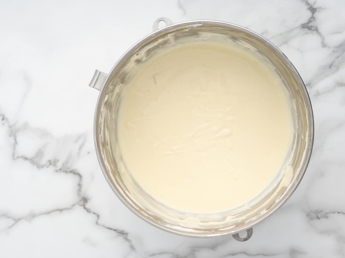 Smooth lemon cheesecake batter in a stand mixer bowl, ready for the blueberries to be folded in.