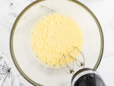 Eggs beaten until pale and foamy in a glass mixing bowl with a hand mixer