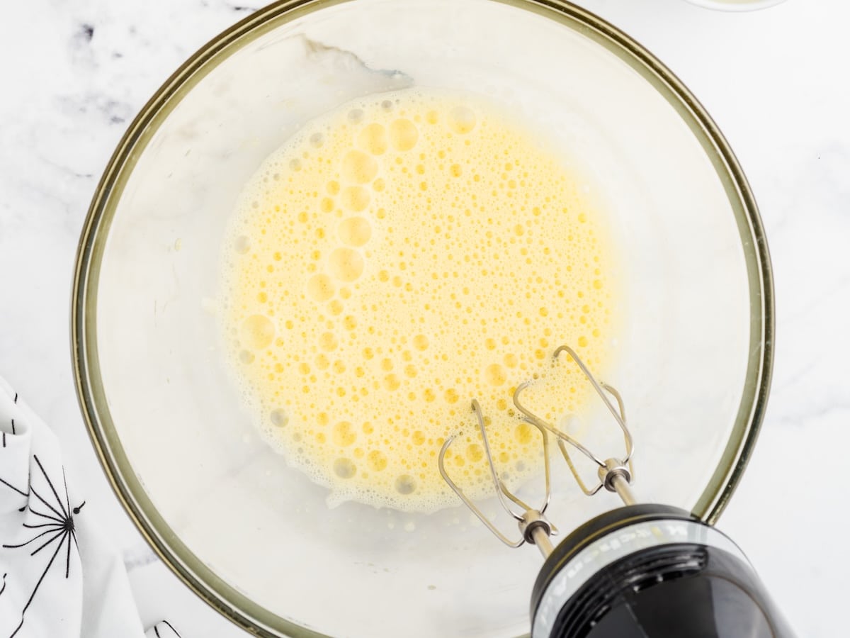 Eggs beaten until pale and foamy in a glass mixing bowl with a hand mixer