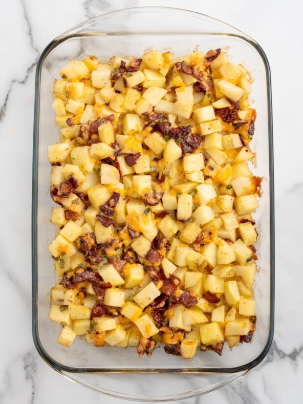 Alt text: Mississippi mud potatoes after the first hour of baking, with crispy bacon and melted cheddar visible, before the final layer of cheese is added.
