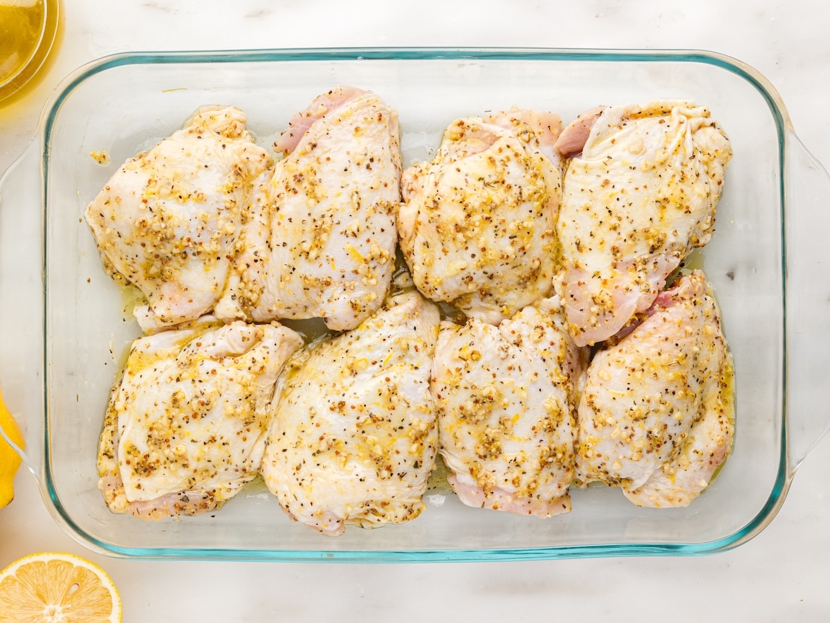 Marinated chicken thighs arranged skin side up in a glass baking dish before going into the oven