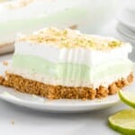 Close-up of creamy Key Lime Pie Lasagna showcasing distinct layers of graham cracker crust, cream cheese filling, smooth key lime layer, and fluffy whipped topping sprinkled with graham cracker crumbs and fresh lime zest.