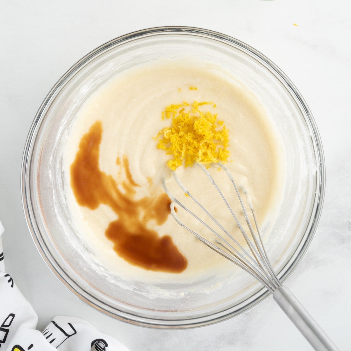 Overhead view of lemon cobbler batter spooned over lemon pie filling and melted butter in a square baking pan, showing the easy layering method before baking this homemade Lemon Cobbler recipe.
