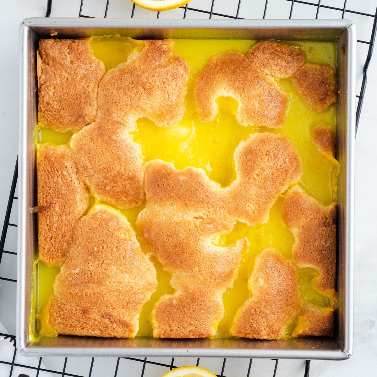 Freshly baked Lemon Cobbler cooling in a square baking pan, featuring a golden brown cobbler topping over a bright, creamy lemon filling.