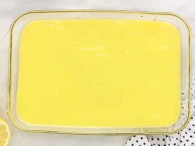 Lemon curd filling spread evenly over the par-baked cake mix crust in a glass 9x13 baking dish.