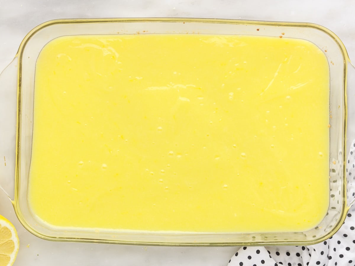 Lemon curd filling spread evenly over the par-baked cake mix crust in a glass 9x13 baking dish.