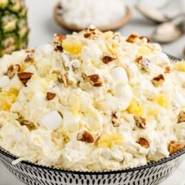 Large serving bowl filled with fluffy Pineapple Fluff made with crushed pineapple, whipped topping, mini marshmallows, coconut, and pecans, ready to serve as an easy no-bake dessert salad.