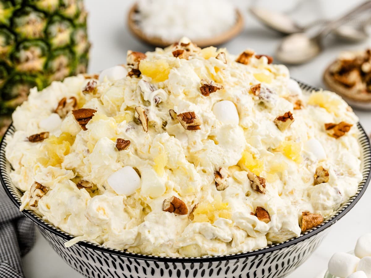 Large serving bowl filled with fluffy Pineapple Fluff made with crushed pineapple, whipped topping, mini marshmallows, coconut, and pecans, ready to serve as an easy no-bake dessert salad.