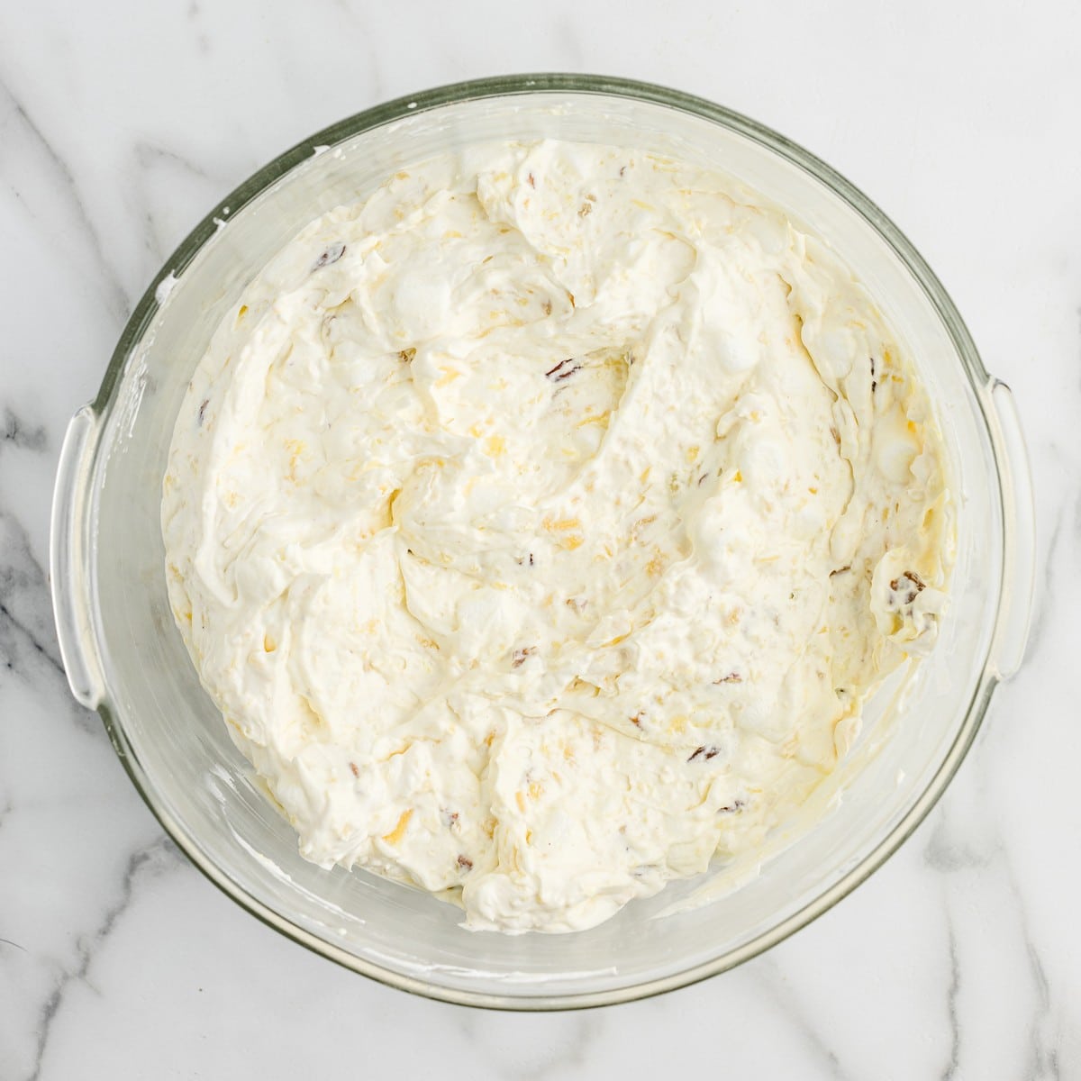 Overhead view of fully combined Pineapple Fluff mixture in a glass bowl, showing the creamy dessert salad before chilling and serving.