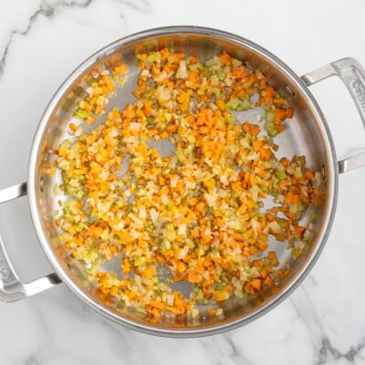 Diced onions, carrots, celery, and garlic saut&eacute;ing in a stainless steel skillet to create the flavorful vegetable base for homemade bolognese sauce.