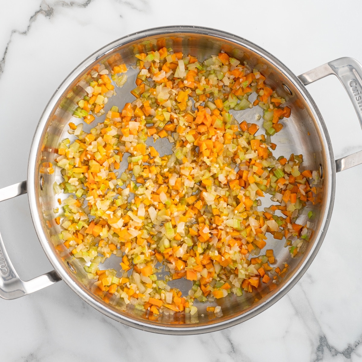 Diced onions, carrots, celery, and garlic saut&eacute;ing in a stainless steel skillet to create the flavorful vegetable base for homemade bolognese sauce.