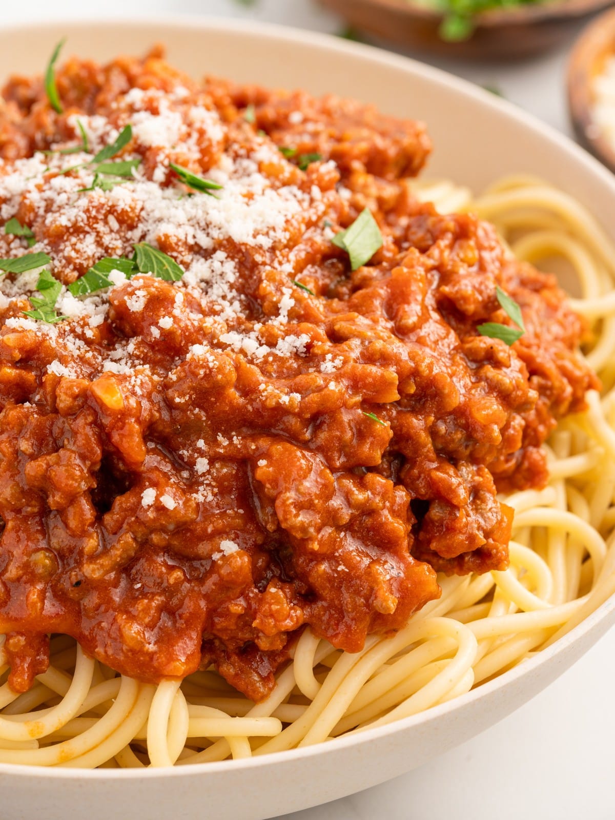 Close-up of homemade Bolognese served over spaghetti, featuring a rich, slow-simmered meat sauce topped with grated Parmesan cheese and fresh parsley for a comforting Italian-inspired meal.