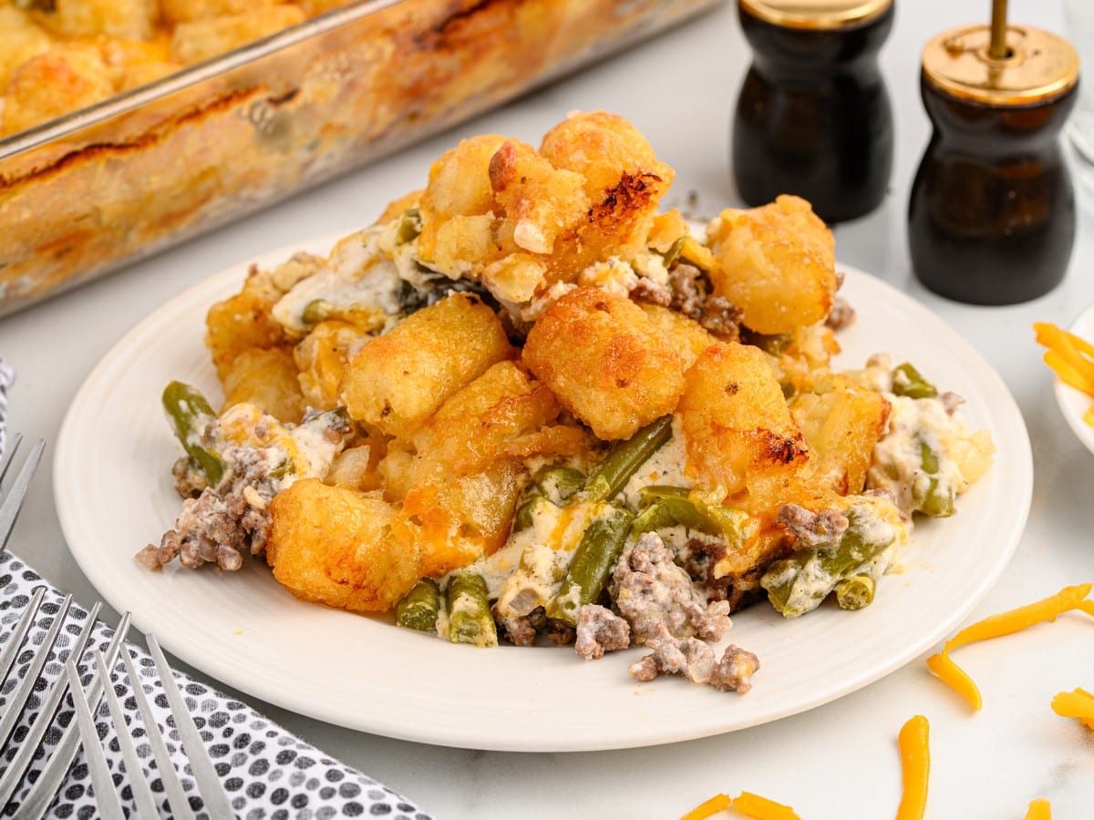 Plated serving of Hamburger Tater Tot Casserole topped with crispy golden tater tots, melted cheddar cheese, seasoned ground beef, green beans, and creamy mushroom sauce.