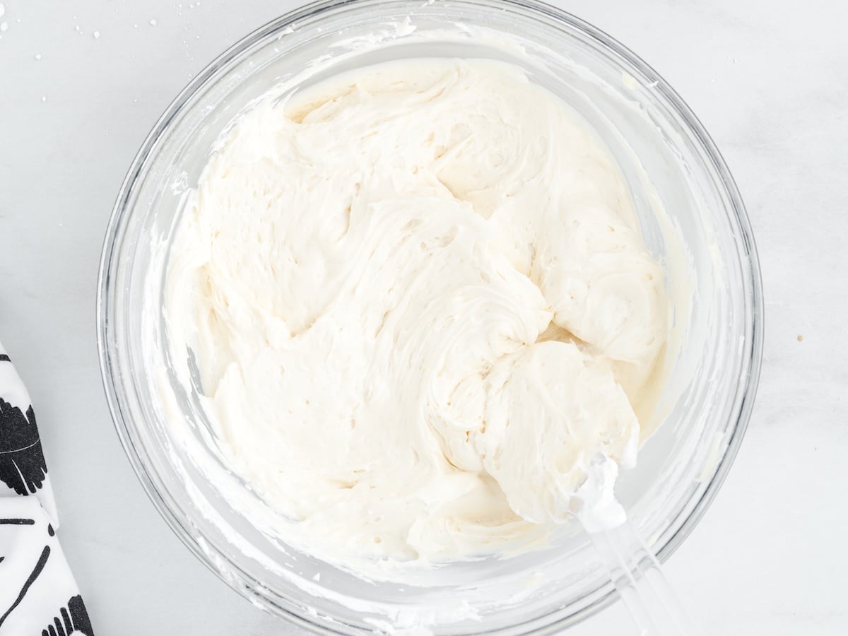 Cream cheese mixture beaten smooth in a glass bowl with a hand mixer