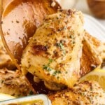 Pinterest pin for crispy oven baked chicken thighs with a wooden spoon lifting one piece, text overlay reads "Crispy, Oven Baked Chicken Thighs, easy for weeknights"