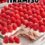 Alt text for the Pinterest pin image: Alt text Overhead shot of raspberry tiramisu in a glass baking dish, topped edge to edge with fresh raspberries, with one square lifted out onto a plate showing the layered ladyfingers, mascarpone filling, and raspberry preserves inside.